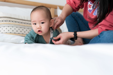 一个年轻的亚裔女性在为儿子换衣服