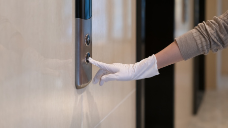 戴着一次性手套的手按电梯按钮