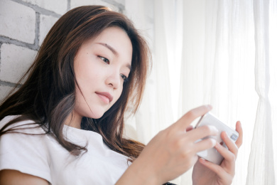 年轻女孩靠在墙边使用手机