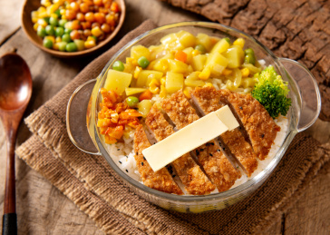 木纹背景上摆放的芝士咖喱鸡排饭