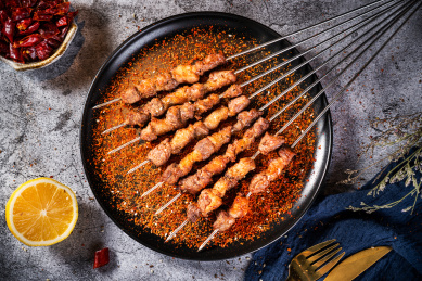 深色背景下放在盘子里的烤羊肉串肥瘦