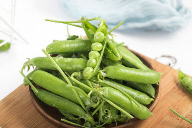 装在木盘中的绿色豌豆荚