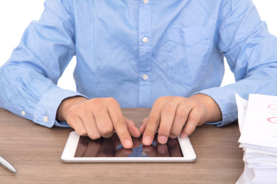 身穿蓝色衬衣的男士在使用ipad办公