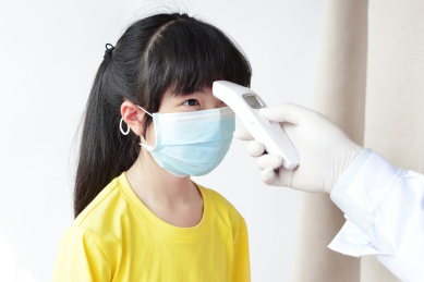 儿科医生用红外线额温枪给女童测量体温