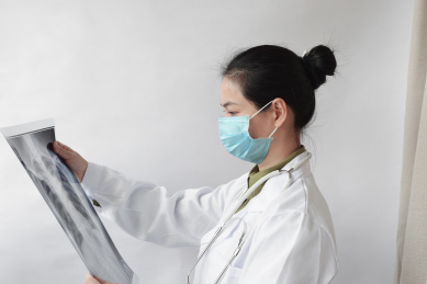 戴着口罩的女医生正在观看肺部CT片