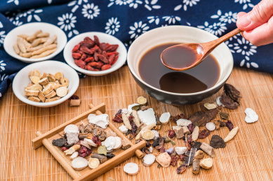 撒在竹席上的各类中药药材和一碗中药药汤