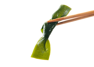 白色背景上筷子夹起的海带结