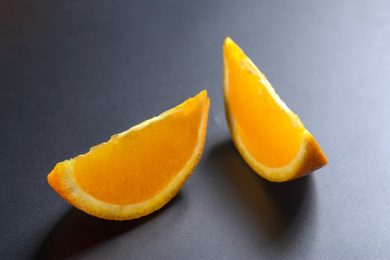 黑色背景前切成瓣的橙子特写