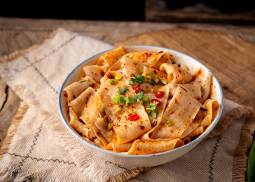 木色背景上餐具里盛放的凉拌面皮