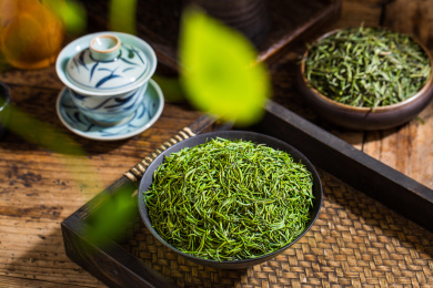 黑色高脚碗装着的绿茶竹叶青干茶叶放茶盘里