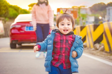 一个母亲在夕阳下看着充满笑容的孩子在奔跑