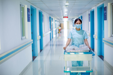 护士推着药瓶车走在医院病房的走廊通道