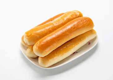 白色背景上餐具里摆放的牛奶棒面包