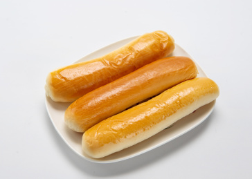 白色背景上餐具里摆放的牛奶棒面包