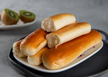 水泥灰背景上餐具里摆放的牛奶棒面包