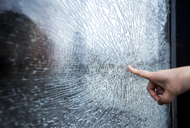 手指头指着破碎的钢化玻璃表面