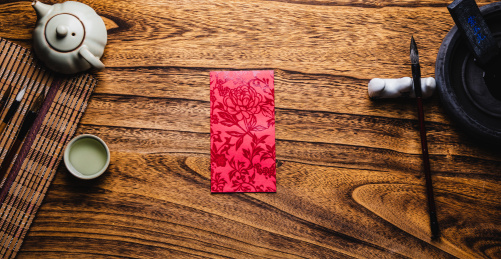 特写木桌上放着笔墨砚台茶杯茶壶和红包