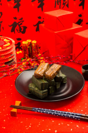 装在黑色盘里的竹叶糯米饭放在红色洒金纸上