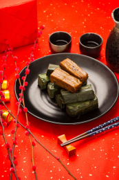 装在黑色盘里的竹叶糯米饭放在红色洒金纸上