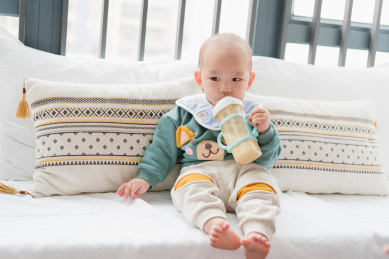 亚裔婴儿坐在飘窗上吃奶