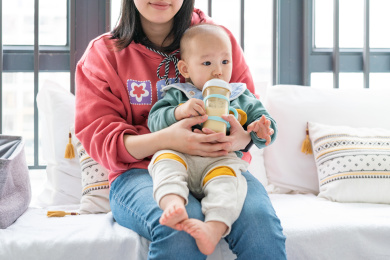 亚裔母亲抱着婴儿坐在飘窗上喂奶