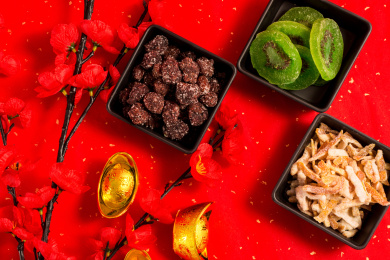 红色背景上装在黑色方形碗中的各类干果零食