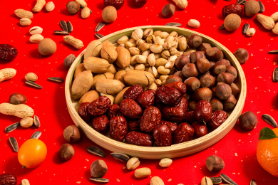 红色背景上装在木盘中的各类干果零食年货