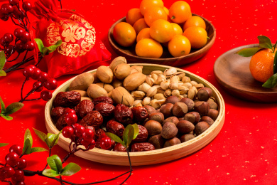红色背景上装在木盘中的各类干果零食年货