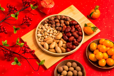 红色背景上装在木盘中的各类干果零食年货