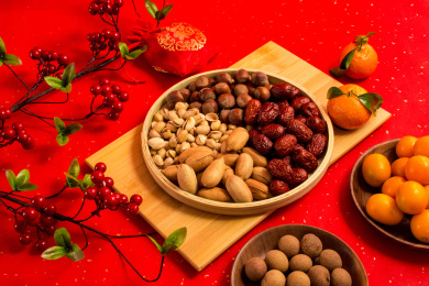 红色背景上装在木盘中的各类干果零食年货