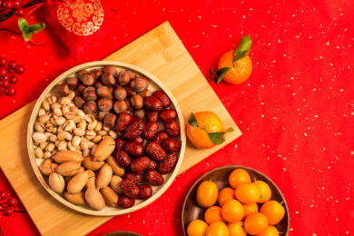 红色背景上装在木盘中的各类干果零食年货