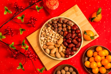 红色背景上装在木盘中的各类干果零食年货