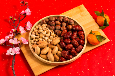 红色背景上装在木盘中的各类干果零食年货