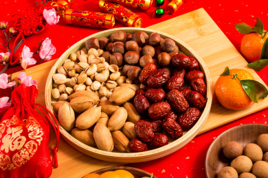 红色背景上装在木盘中的各类干果零食年货