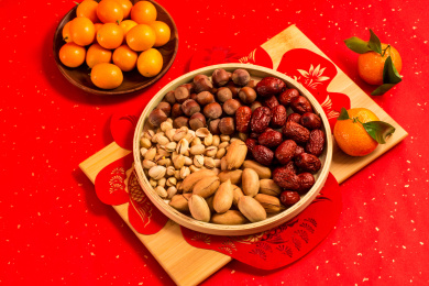 红色背景上装在木盘中的各类干果零食年货