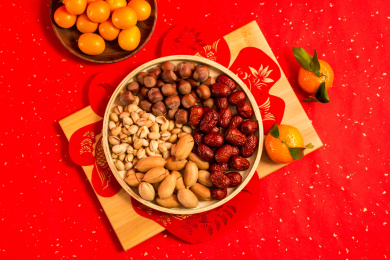 红色背景上装在食盒中的各类干果零食年货