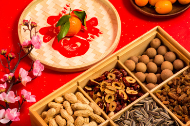 红色背景上装在食盒中的各类干果零食年货