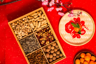 红色背景上装在食盒中的各类干果零食年货