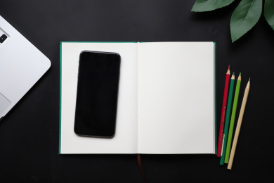 黑色办公桌上放着本子和手机