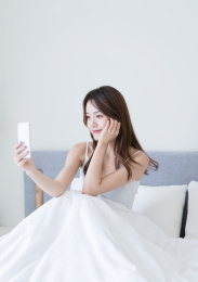 漂亮的长发女生坐在床上自拍