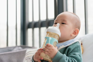 亚裔婴儿坐在飘窗上吃奶