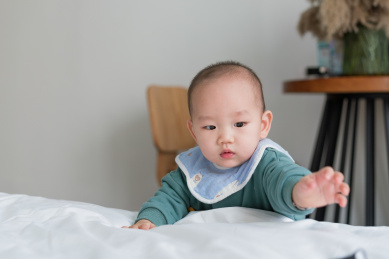 房间里的亚裔婴儿伸手去拿东西