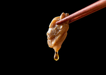 黑色背景上筷子夹花起的五香花蛤肉