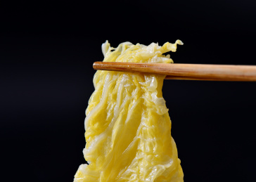 黑色背景上筷子夹起的酸白菜