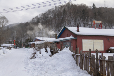 中国雪谷村庄冬季积雪的屋子烟囱飘着烟
