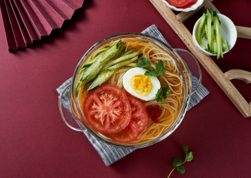 深红色背景上餐具里盛放的朝鲜冷面