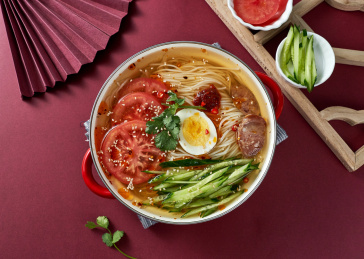 深红色背景上餐具里盛放的朝鲜冷面