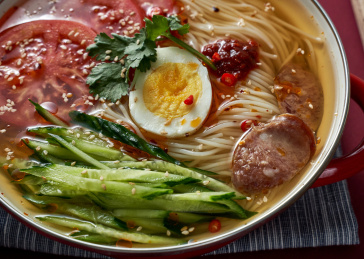 深红色背景上餐具里盛放的朝鲜冷面