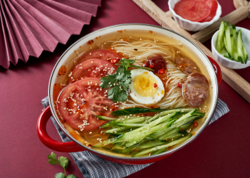 深红色背景上餐具里盛放的朝鲜冷面