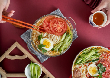 深红色背景上餐具里盛放的朝鲜冷面